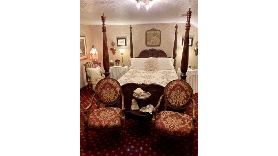 Carved four poster bed with tapestry armchairs in the Parisian Dreams Bedchamber Suite