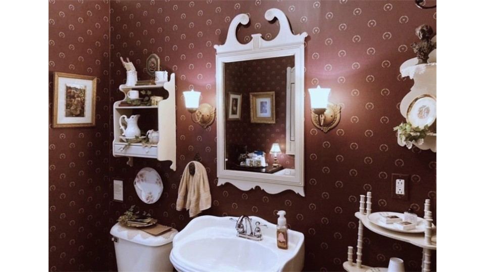 Bathing room with rich red wall coverings and antique mirror